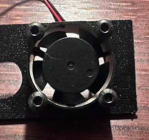 A small DC fan screwed to a 3D printed assembly