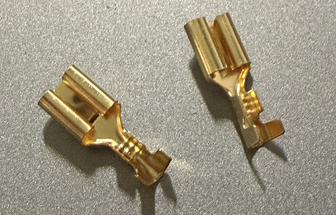 A picture of two gold-colored female spade connectors.