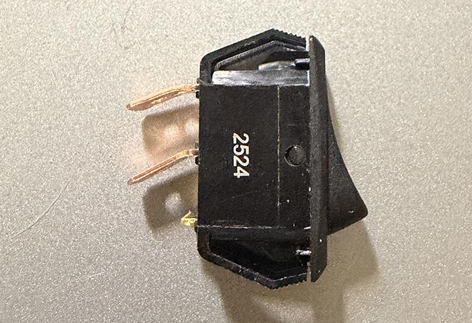 A picture of a SPST rocker switch with the terminals bent down at a 45 degree angle.