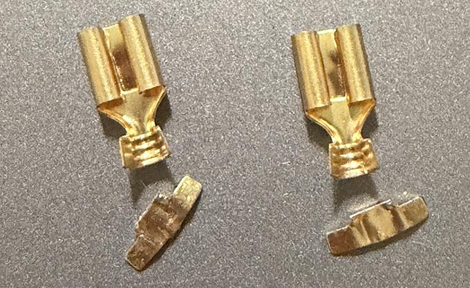 A picture of two gold-colored female spade connectors, modified with the last set of crimp connectors removed.